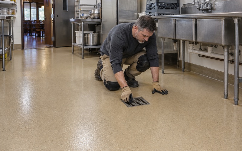 A stainless drain grate set flush into a new urethane cement floor in a DeKalb restaurant kitchen.